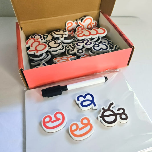 Box of colorful telugu letter magnets with a pen on a white board
