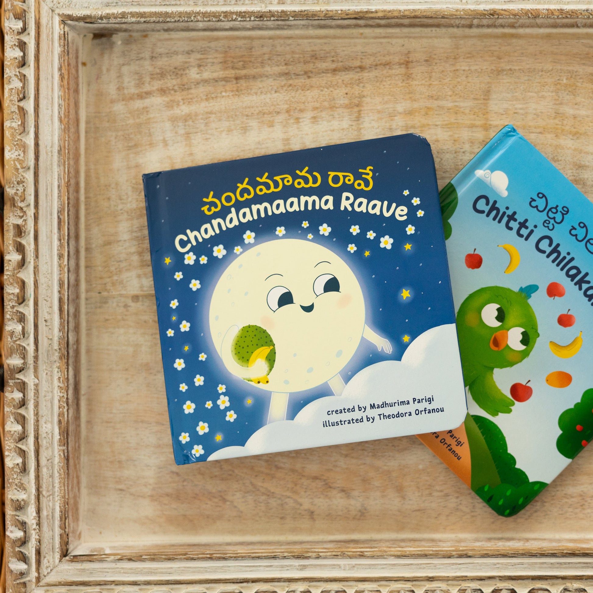 Two children's books on a wooden surface with a decorative frame.